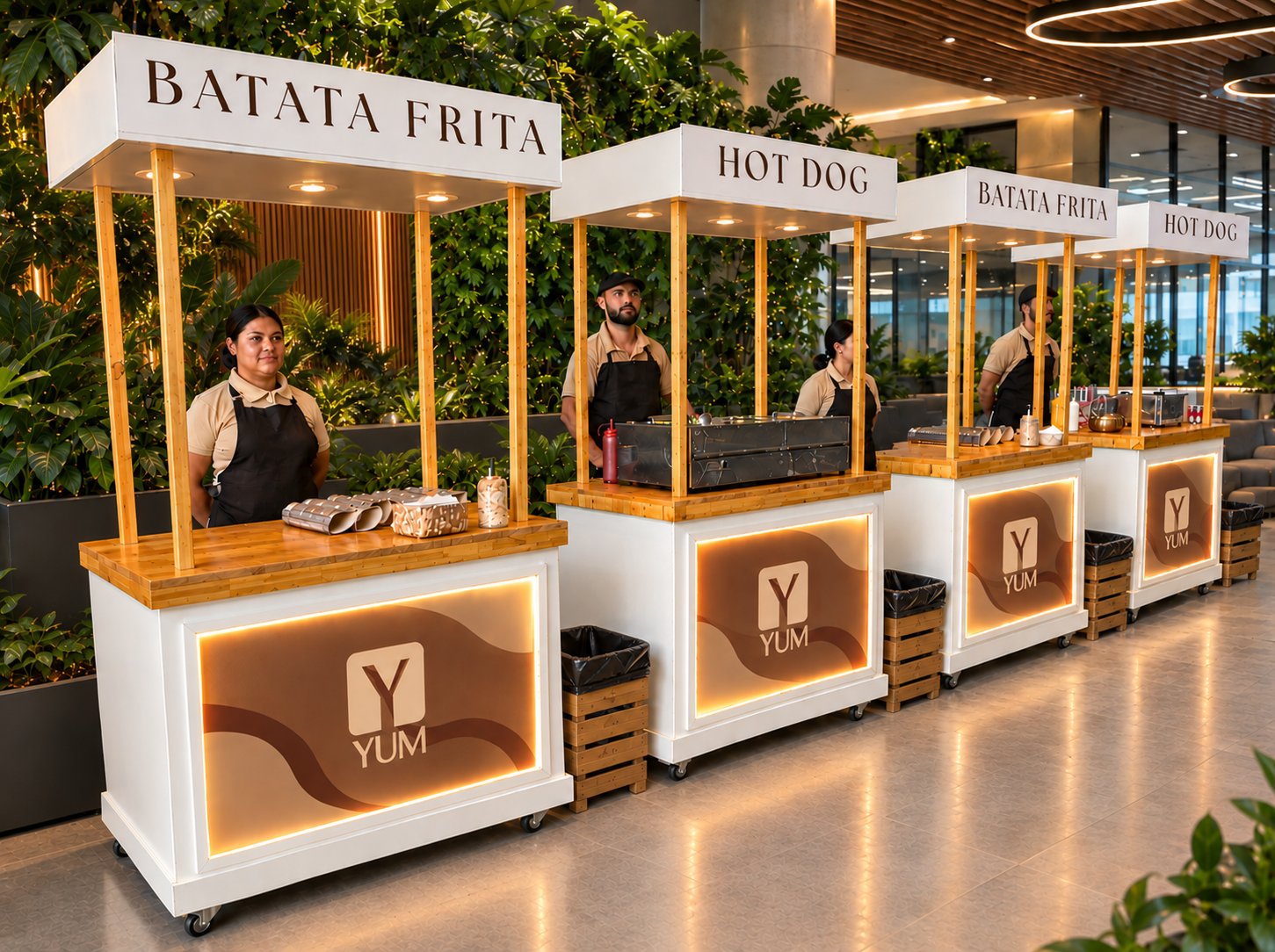 Quatro carrinhos YUM de batata frita e hot dog com painéis iluminados, tampo em madeira e atendentes uniformizados